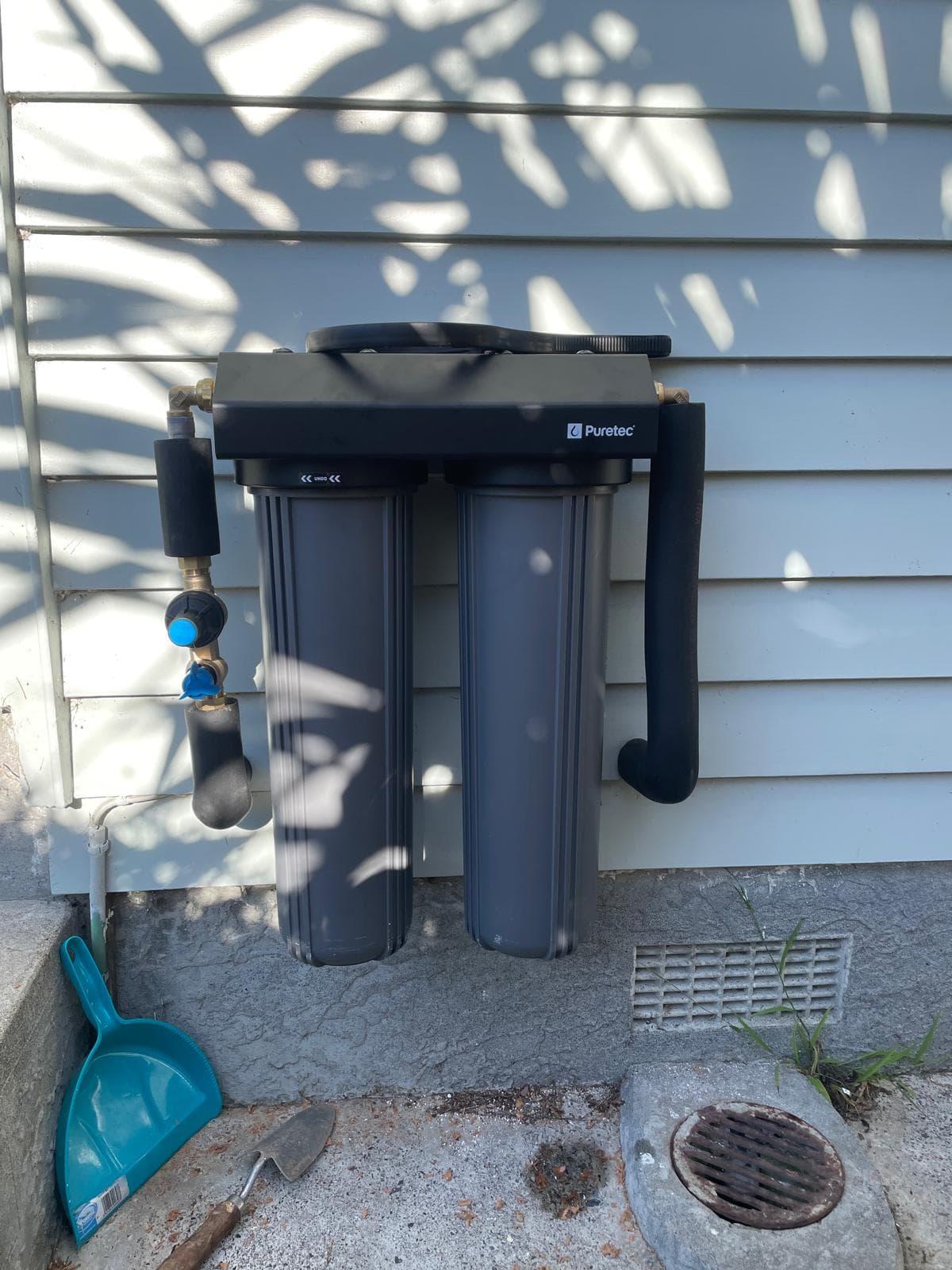 Puretec twin-cartridge whole-house water filter installed on an exterior weatherboard wall