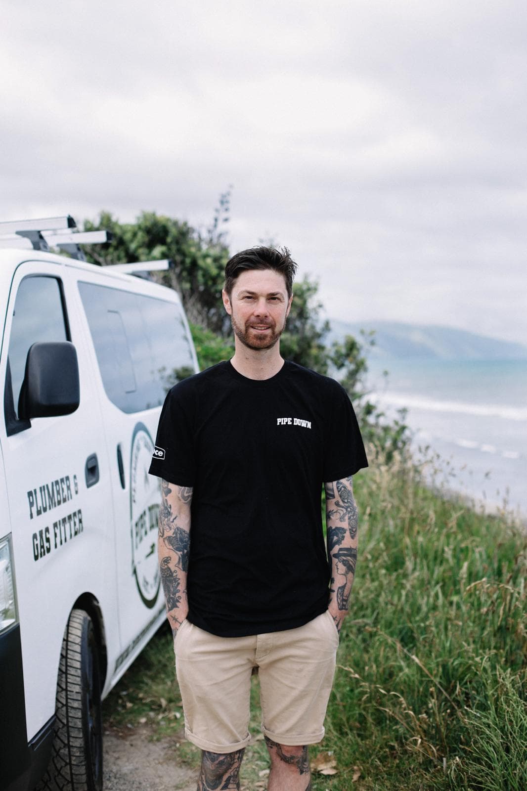 Tony Kane, owner of Pipe Down Plumbing, standing in front of his signwritten van on the Kapiti coast